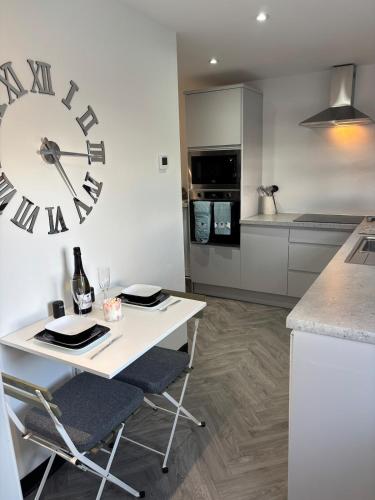 a kitchen with a table and a large clock on the wall at Little Woodlands Chalet with Private Garden & Hot Tub in Llancarvan