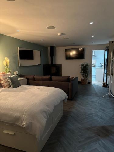 a bedroom with a large bed and a couch at Little Woodlands Chalet with Private Garden & Hot Tub in Llancarvan