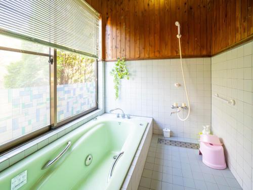 a bathroom with a tub and a window and a pink toilet at Beautiful Nasu, the center of Nasu, Up to 12 people, 3 bedrooms, BBQ on the deck, night karaoke in Nasu