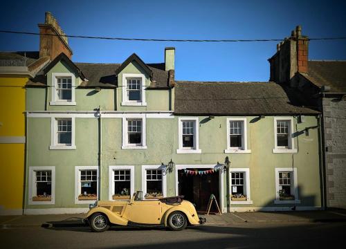 an old yellow car parked in front of a building at The Wigtown Ploughman in Wigtown