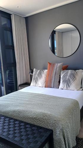 una camera con un grande letto e uno specchio di City Slick Hideaway a Città del Capo