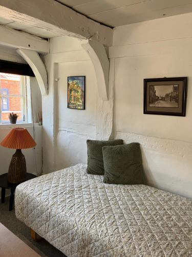 a bedroom with a bed and a table with a lamp at Madam Bundsens Huse in Assens