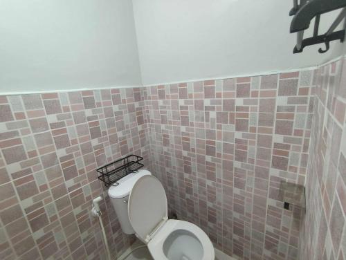 La salle de bains est pourvue de toilettes et d'un mur carrelé. dans l'établissement Lorna's Home, à Bil-isan