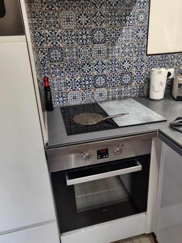 a kitchen with a stove and a tile wall at Petit chalet avec piscine privée in Lumbin