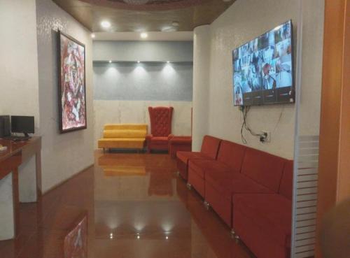 Una sala de estar con un sofá rojo y un televisor de pantalla plana. en Hotel The Grand Ranjeet, en Indore