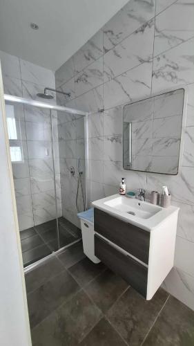 a bathroom with a sink and a shower and a mirror at Cosy studio close to Qawra Beach in St. Paul's Bay