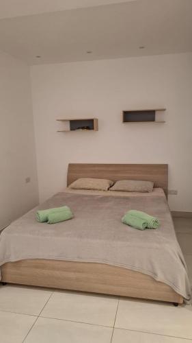 a bedroom with a large bed with two green pillows at Cosy studio close to Qawra Beach in St. Paul's Bay