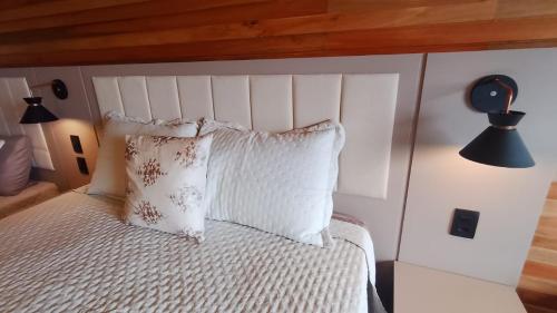 a bedroom with a white bed with a wooden headboard at Cabana Alpen Ville 01 - Rural com Banheira de Hidromassagem in Bom Jardim da Serra