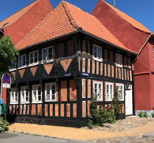 a black and white building with a red roof at Madam Bundsens Huse in Assens