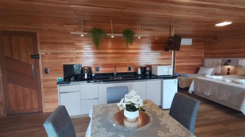 a kitchen with a table with flowers on it at Cabana Alpen Ville 01 - Rural com Banheira de Hidromassagem in Bom Jardim da Serra