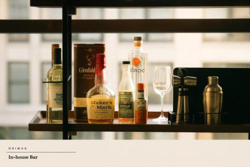 a shelf with bottles of wine and a glass at Apartment by Spitalfields & Liverpool Street Station in London
