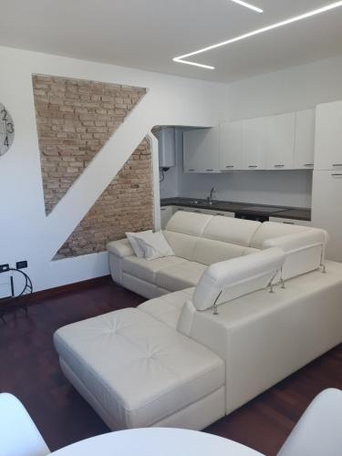 a living room with white couches and a brick wall at APPARTAMENTO LAKE GARDA ibiscus di Francia in Desenzano del Garda