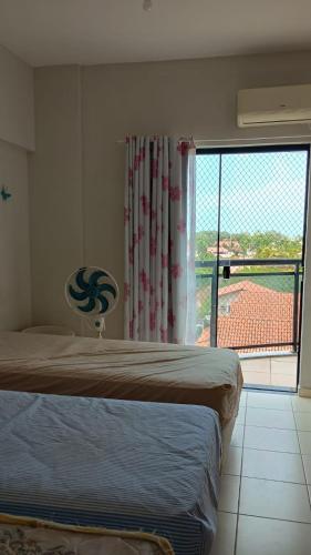 ein Schlafzimmer mit einem Bett und einem großen Fenster in der Unterkunft Salinópolis Praia in Salinópolis