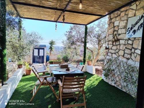 a patio with a table and chairs on the grass at Seleucia DaR Umm Qais in Um Qeis