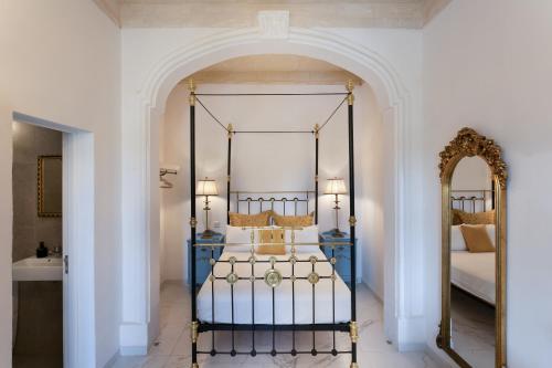 Valletta Townhouse Suite with a Maltese Balcony في إيل فورجانا: غرفة نوم مع سرير بأربعة أعمدة ومرآة