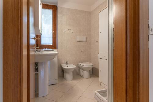 a bathroom with a sink and a toilet and a window at Trilo La Rindela in Folgaria