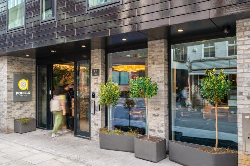 a woman walking outside of a building with potted plants at Point A Hotel London Shoreditch in London