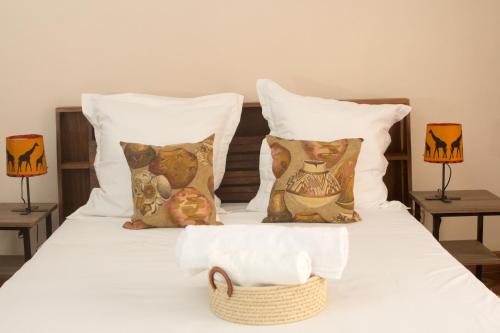 a white bed with pillows and a basket on it at COCOONING HOME # Centre-Ville # Confort # Charmant # マダガスカルのゲストハウス in Antananarivo
