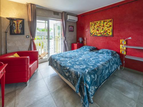 a bedroom with a bed and a red wall at Le Flamboyant 309, magnifique appartement avec piscine in Saint-Gilles les Bains