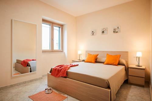 sypialnia z łóżkiem z pomarańczowymi poduszkami i lustrem w obiekcie Casa Vacanze La Trinità w mieście Ravello