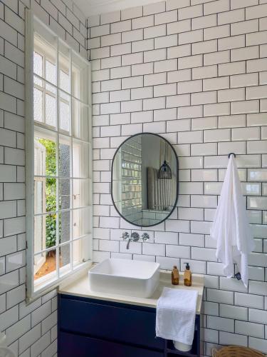 a white bathroom with a sink and a mirror at LadyBird Cottage in Durban