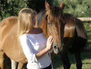 Una donna in piedi accanto a un cavallo marrone di Casa Masseria Le Ville a Peschici