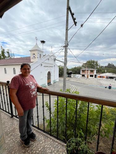 a man standing on a balcony in front of a church at Pakarina Hospedaje in Cotacachi