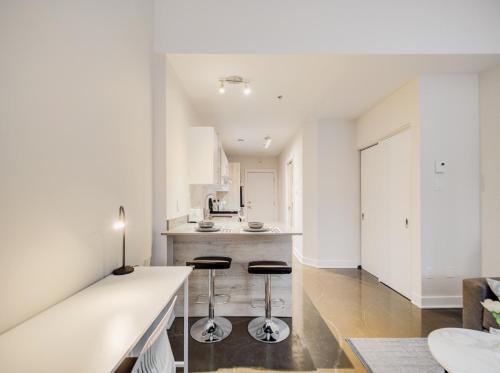 a white kitchen with two stools in the middle at Confort et style en plein Montréal in Montréal