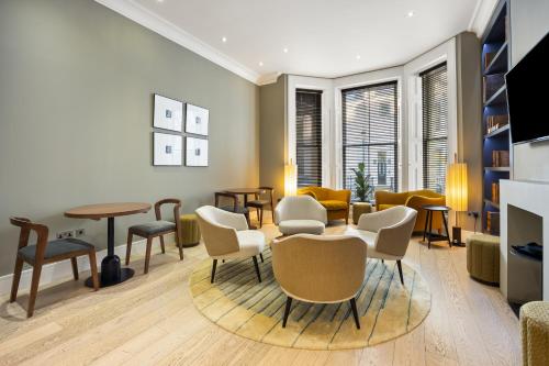 a living room with a table and chairs at Kula London - Kensington in London
