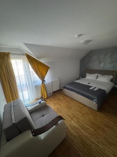 a bedroom with a bed and a couch and a window at Sophia Maria Caciulata in Caciulata