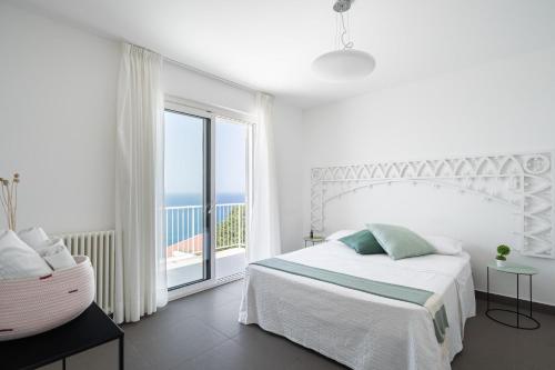 a white bedroom with a bed and a large window at Villa Stellata in Naso