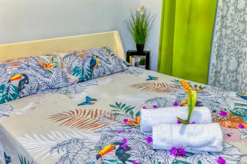a bed with a bedspread with birds and towels at Pom'kanelle in Le Gosier