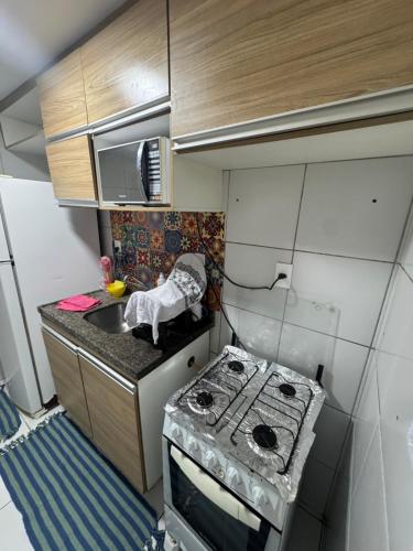 een kleine keuken met een fornuis en een spoelbak bij Apt Eldorado perto da praia confortável para 2 a 5 pessoas in São Luís