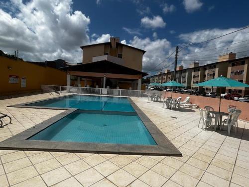 een zwembad met stoelen en parasols op een gebouw bij Apt Eldorado perto da praia confortável para 2 a 5 pessoas in São Luís