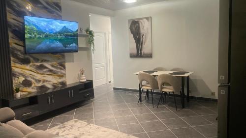 a dining room with a table and a tv on the wall at T3 moderne avec piscine proche de Family Plaza in Matoury
