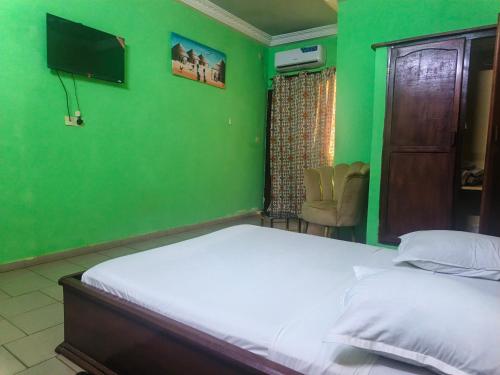 Dormitorio verde con cama y TV en Badenk Hôtel, en Yaoundé