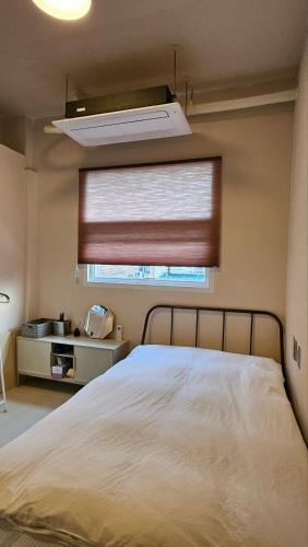 a bedroom with a bed and a window with a blind at 협재10분 영주스테이 in Suwŏn-ni