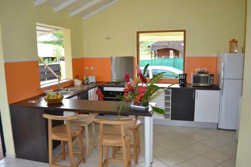 a kitchen with a island with chairs and a counter top at Maison confortable avec piscine à Goyave in Goyave