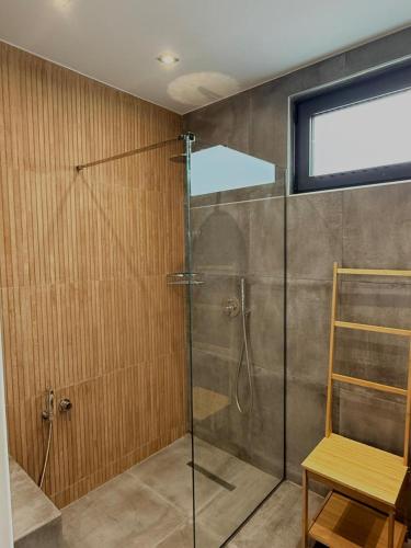 een douche met een glazen deur en een houten stoel bij Interni Villa by A&D Properties in Porto Rafti