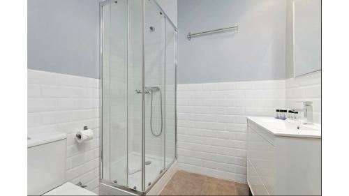 Un baño blanco con ducha y lavabo. en Comfy 1 BR Flat - Bright, Central & Calm, en Madrid