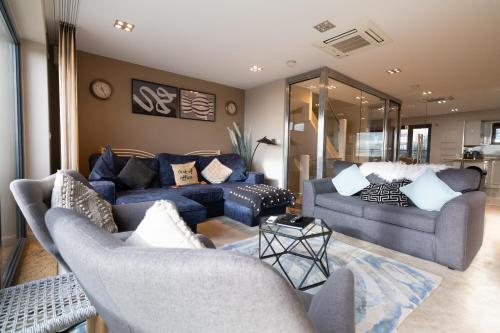a living room with two blue couches at Stunning Swansea Marina beach house with sea views in Swansea