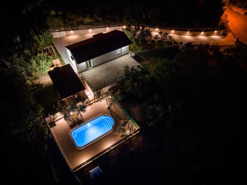 an overhead view of a swimming pool in front of a house at night at Holiday House Olive in Solin