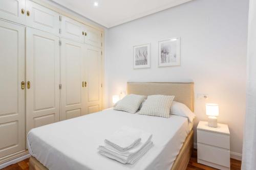 1 dormitorio blanco con 1 cama grande con armarios blancos en Cozy 1BD Apartment in Alonso Martínez, en Madrid