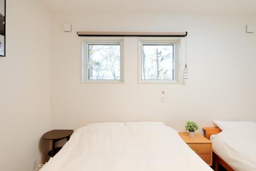長野市にあるPeak Hakuba 峰白の白いベッドルーム(ベッド2台、窓2つ付)が備わります。