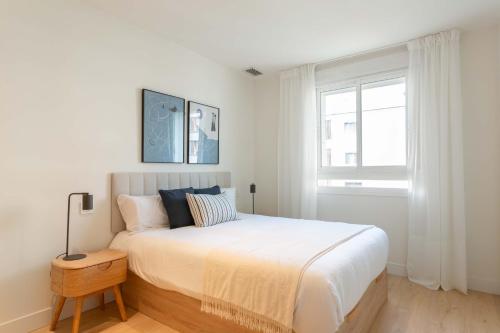 a white bedroom with a large bed and a window at Modern Stay in Plaza Castilla in Madrid