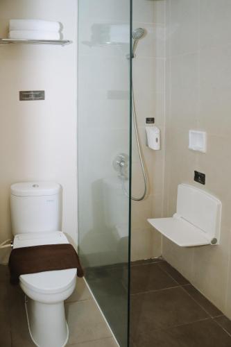 a bathroom with a toilet and a glass shower at The Bountie Hotel and Convention Centre Sukabumi in Sukabumi
