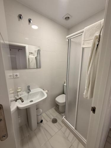 a white bathroom with a toilet and a sink at Hostal Merino Jédula in Jedula