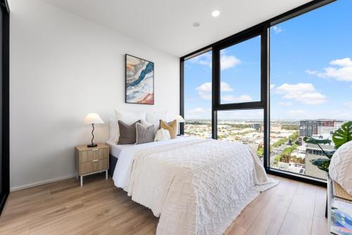 a bedroom with a large white bed and large windows at City sky view self service apartment free parking in Adelaide