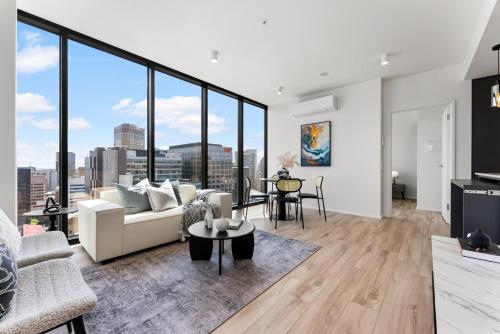 a living room with white furniture and large windows at City sky view self service apartment free parking in Adelaide