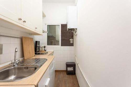 a white kitchen with a sink and a counter at Urban Nest Retreat in Madrid